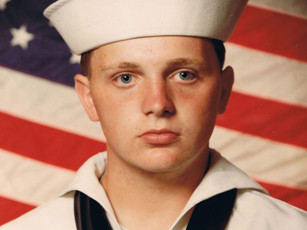 Young sailor in front of American flag